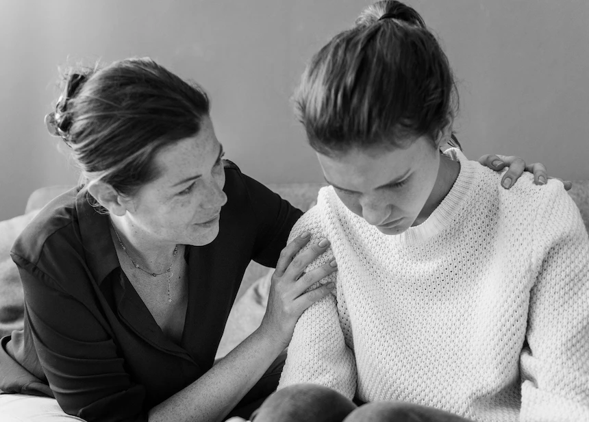 Madre consolando a su hija en duelo complicado, terapia y apoyo emocional