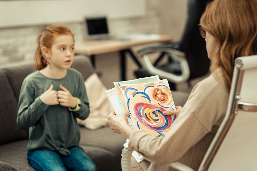 Terapeuta infantil aplica técnica psicodinámica con niña con TEA mediante interpretación de dibujo en sesión de terapia